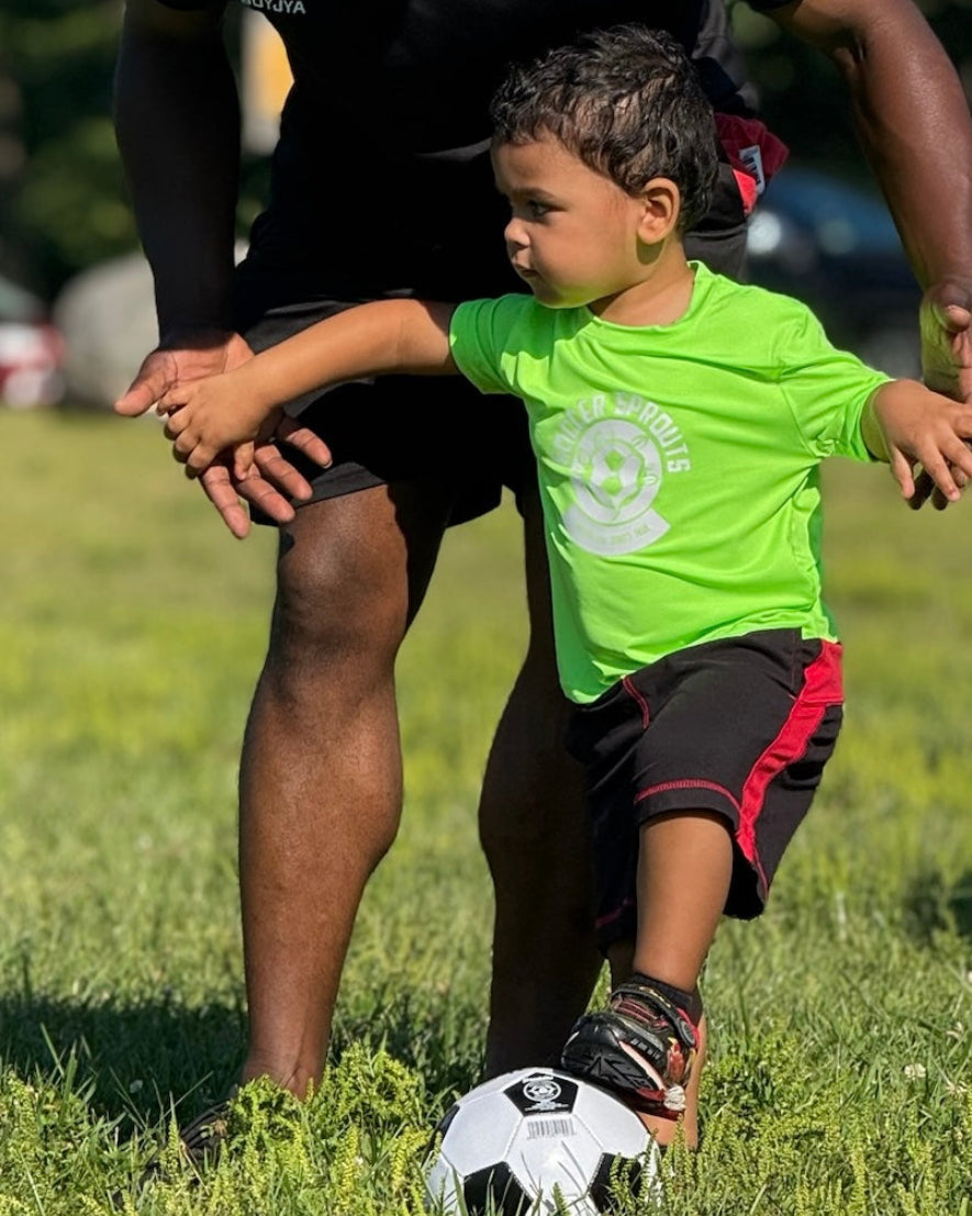 Man and child playing soccer on a grassy field